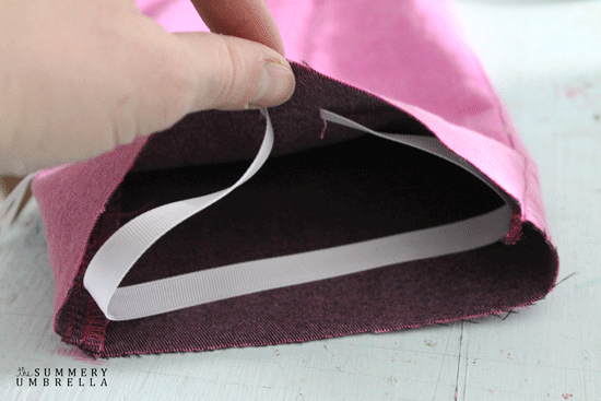 Pink jeans pencil bag with white ribbon closure.